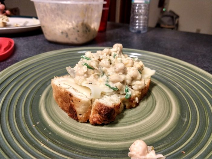 Chickpea salad spread on a piece of toast with swiss cheese 