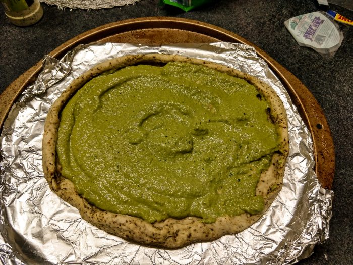 jalapeno pizza dough rolled out with pesto 